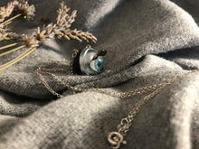 Load image into Gallery viewer, Side view of aqua doll eye necklace displaying the lashes that will flutter when the doll eye blinks
