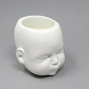 doll head pot in white shown at side angle on grey background, showing detailed ears and face