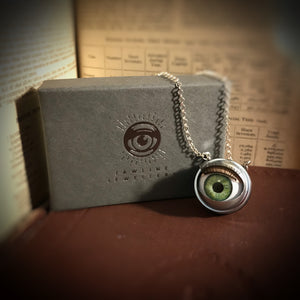 green doll eye necklace shown with jewellery box - box is grey with silver foil eye logo