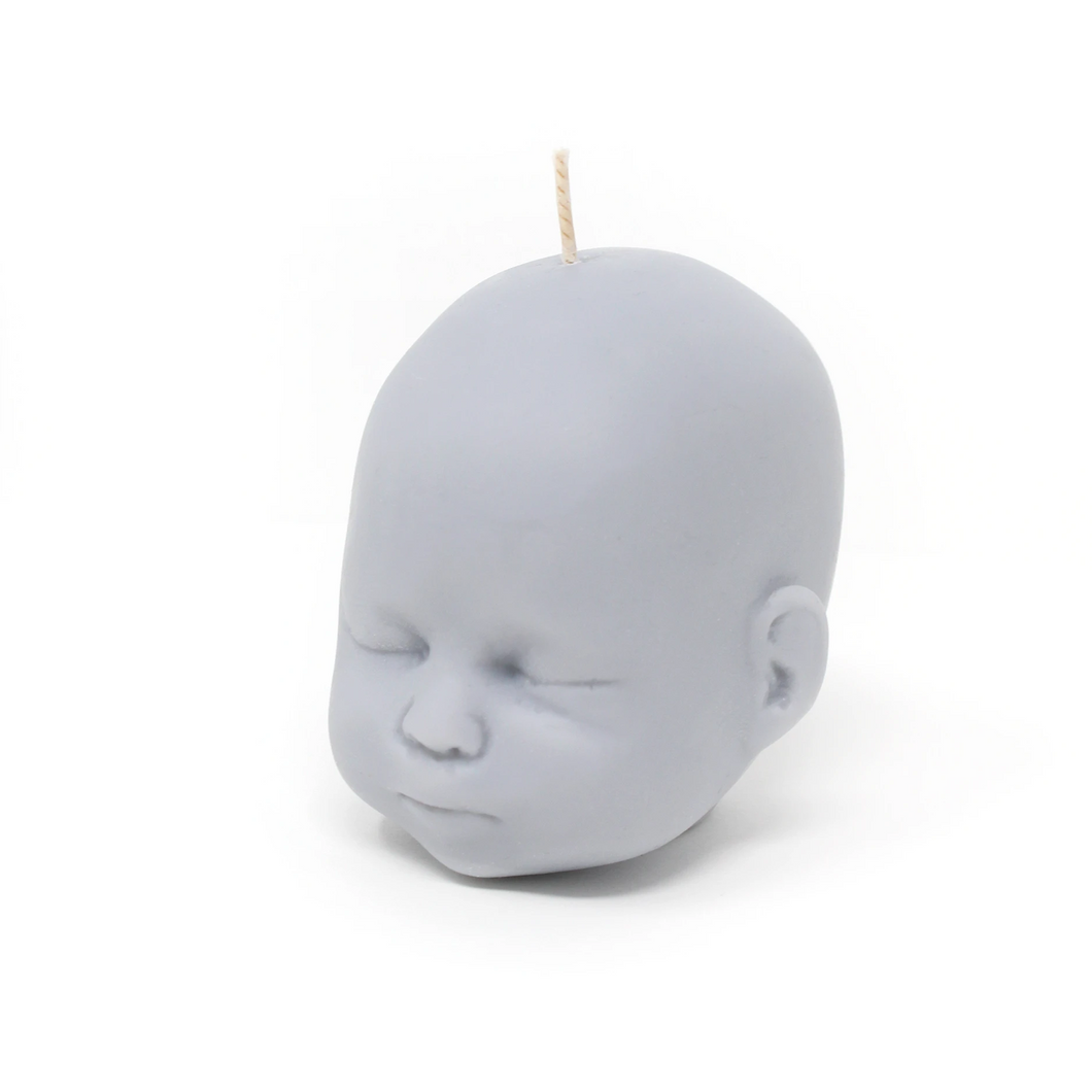 Grey doll head shaped candle on white background