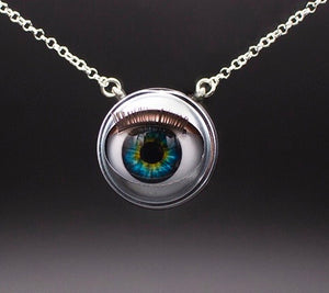 Blinking doll eye necklace with bright green and blue iris on sterling silver chain with grey beckground