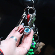 Load image into Gallery viewer, doll eye keychain with blue eye and long lashes, held by someone with long red glitter nails