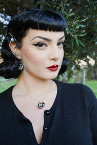 pin up model with classic makeup wears matching green doll eye necklace and earrings