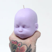 Load image into Gallery viewer, Purple doll head candle being balanced on tattooed hand