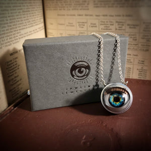 Blue and green eyeball with jewellery box - jewellery box is grey with silver foil showing logo and text of Jawline Jewellery