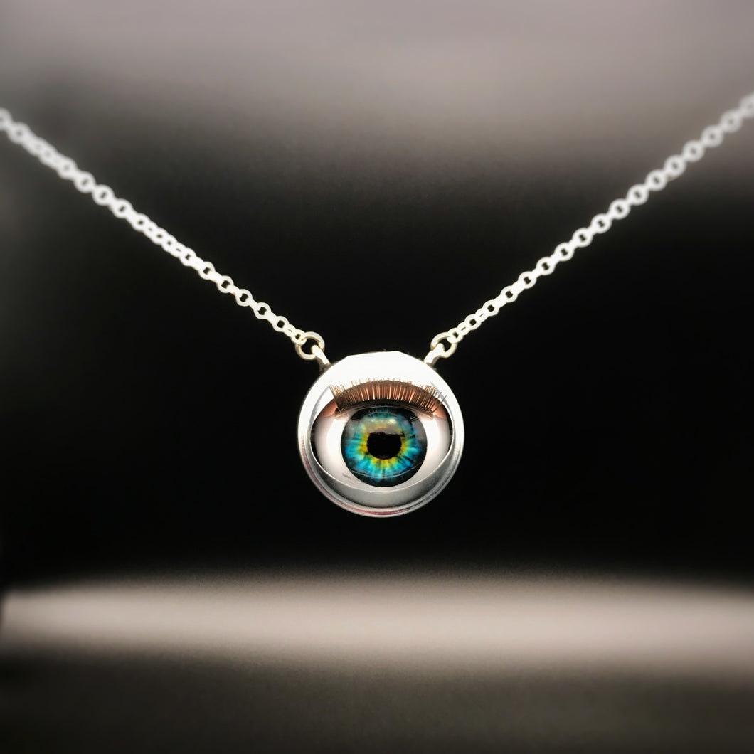 Silver necklace with doll eye pendant and green and blue iris, with long eye lashes