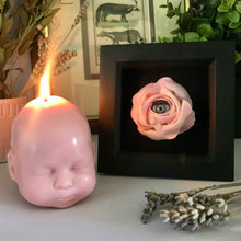 Load image into Gallery viewer, A warm photo featuring dried plants and flowers, with a pink doll head candle lit, sat next to black box frame with pink craying rose with grey doll eye in the middle of the flower