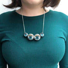 Load image into Gallery viewer, Spider necklace made from 4 doll eyes in the shape of spider eyes worn by model in plain blue top showing the bright eye colour (blue)