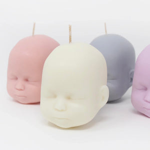 group shot showing different colours available of doll hed candles, white, peach, grey and purple on white background