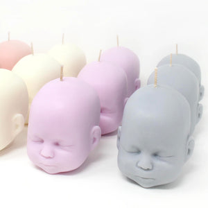 group shot showing different coloured candles focusing on pink and grey doll heads