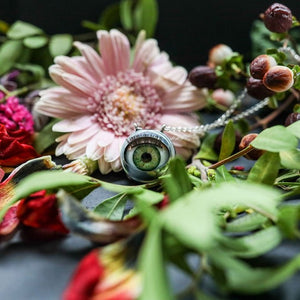 green doll eye shown on drk background with flowers