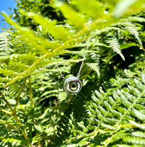 jawline jewellery green doll eye necklace in the sun hung on ferns