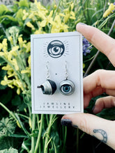 Load image into Gallery viewer, hand holdign backing card with earrings hung on, background of flowers