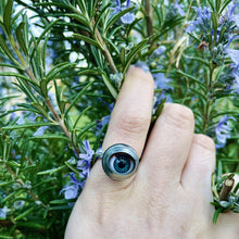 Load image into Gallery viewer, doll eye ring being worn on second finger with hand touching some rosemary