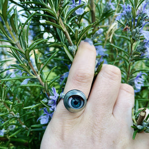 doll eye ring being worn on second finger with hand touching some rosemary