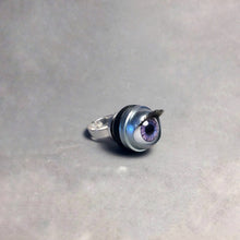 Load image into Gallery viewer, purple doll eye ring shown at side angle allowing you to see the lashes and height of ring (it is quite chunky) shown on grey background