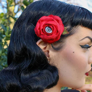 Pin Up style model wearing Red Hair rose with Grey Blinking eyeball in the middle of the flower
